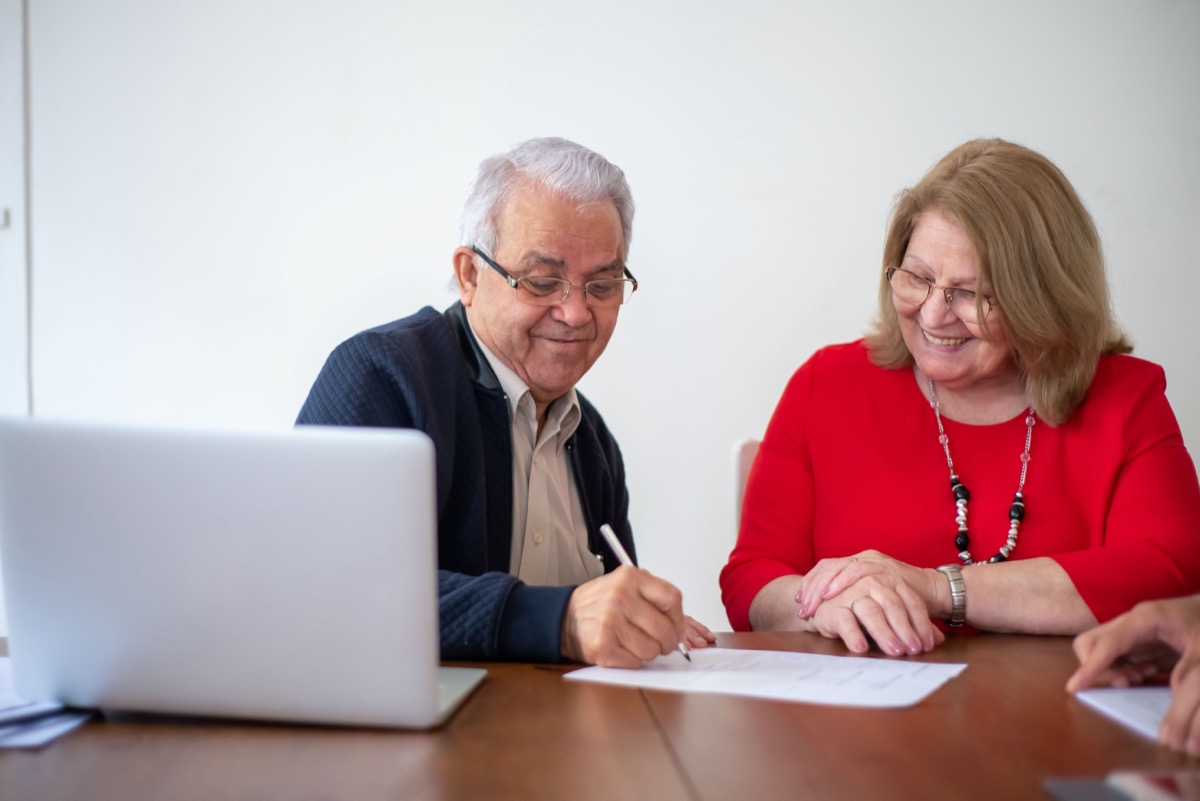 A senior couple reviewing their Medicare plan options with paperwork and a laptop